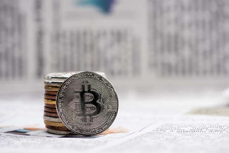 KYIV, UKRAINE - NOVEMBER 1, 2021: close up of metallic bitcoins on printed newspaper