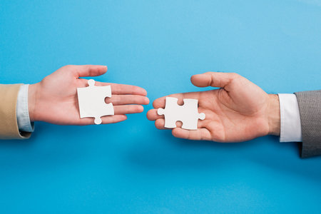 top view of male and female hands with jigsaw on blueの写真素材