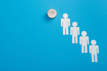 top view of white paper cut people near bitcoin on blueの写真素材