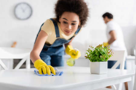 blurred african american woman cleaning dining table with rag near blurred boyfriendの写真素材
