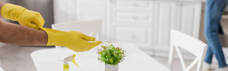 cropped view of man wearing yellow rubber gloves with blurred woman on background, bannerの写真素材