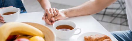 cropped view of couple holding hands during breakfast, bannerの写真素材