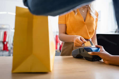 cropped view of customer paying by credit card near african american sales assistant in boutiqueの写真素材