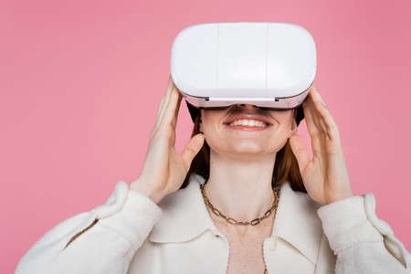 Freckled and smiling woman using vr headset isolated on pinkの写真素材