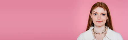 Pensive woman in jacket and necklaces looking at camera isolated on pink, banner