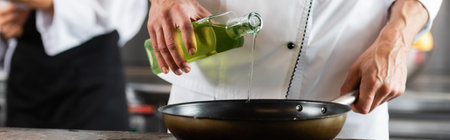 Cropped view of chef pouring olive oil on frying pan in kitchen, bannerの写真素材