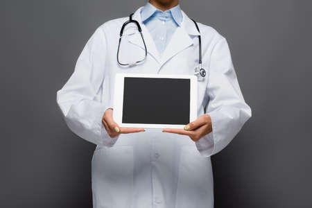 Cropped view of doctor showing digital tablet with blank screen isolated on greyの写真素材