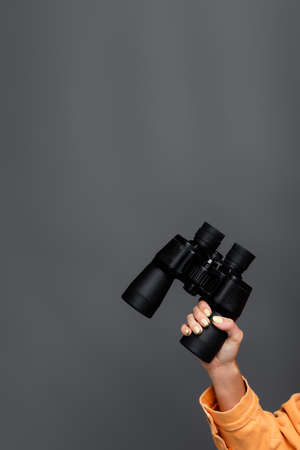 Cropped view of tourist holding binoculars isolated on greyの写真素材