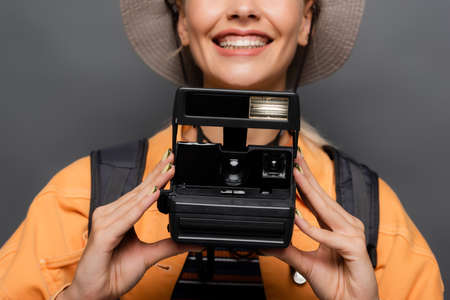 Cropped view of smiling tourist holding vintage camera isolated on grey
