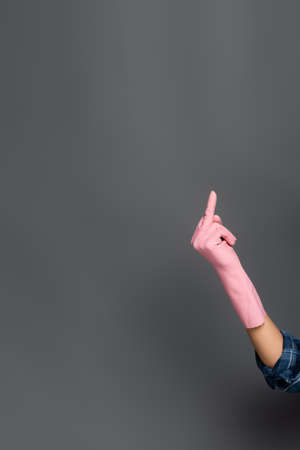 Cropped view of plumber in rubber glove showing middle finger gesture on greyの写真素材