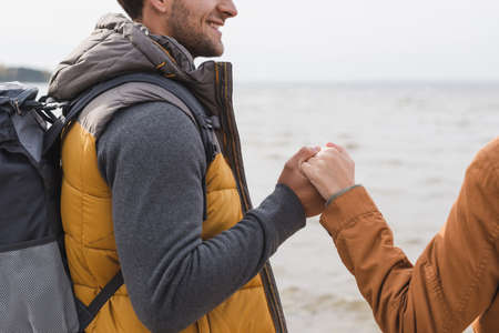cropped view of couple holding hands while having walk near lake