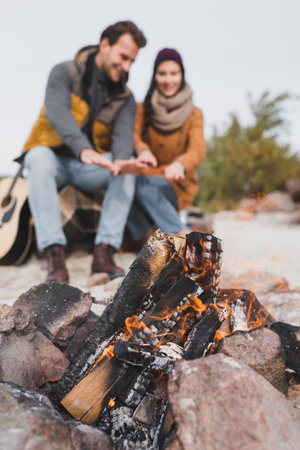 selective focus of bonfire near blurred couple warming during autumn walkの写真素材