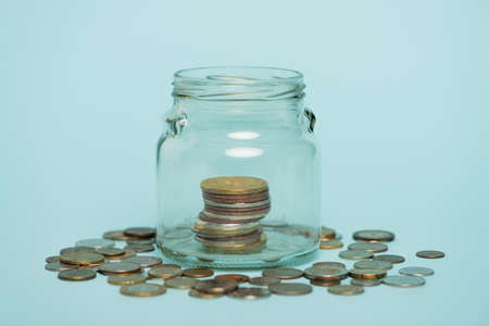 glass jar with money near scattered coins on blue background, anti-corruption concept