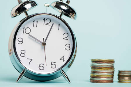 vintage alarm clock near stacked coins on blue background, anti-corruption conceptの写真素材