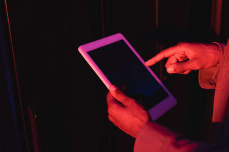 cropped view of african american programmer pointing at mobile phone with blank screen in data centerの写真素材