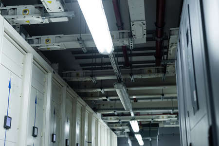 low angle view of closed servers in data center with fluorescent lamps, cyber security concept