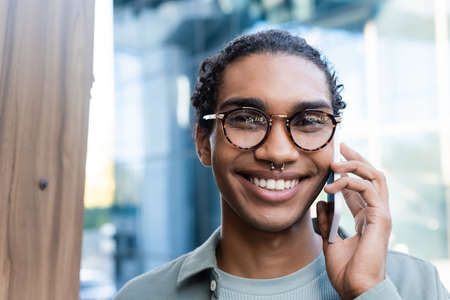 portrait of african american man in eyeglasses calling on cellphone while looking at camera