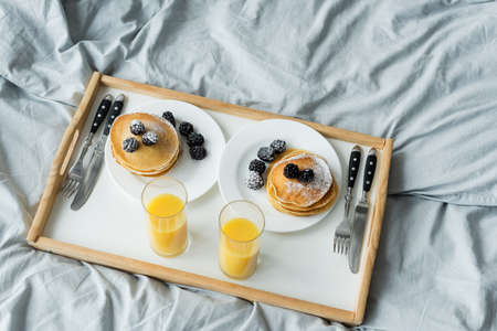 high angle view of blackberries on tasty pancakes near glasses on orange juice on trayの写真素材