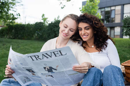 joyful lesbian couple reading travel newspaper in parkの写真素材