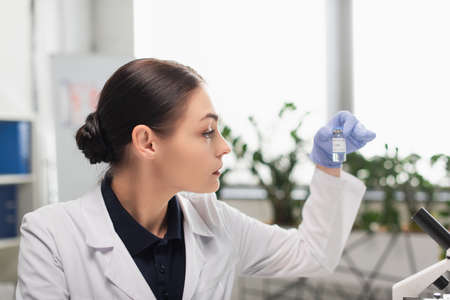 scientist in latex glove holding coronavirus vaccine in laboratoryの写真素材