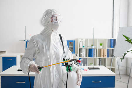doctor in hazmat suit holding sprayer while making disinfection of laboratoryの写真素材