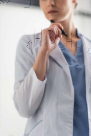 partial view of chemist standing near formulas on glass board in labの写真素材