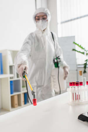 blurred doctor in protective suit making disinfection of laboratory with sprayerの写真素材