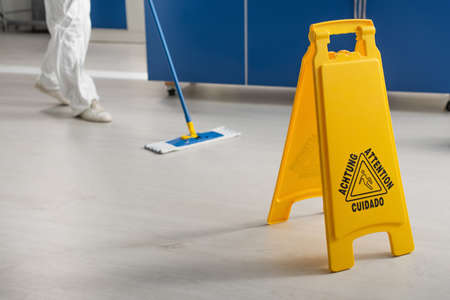 cropped view of doctor wiping floor in laboratory near attention boardの写真素材