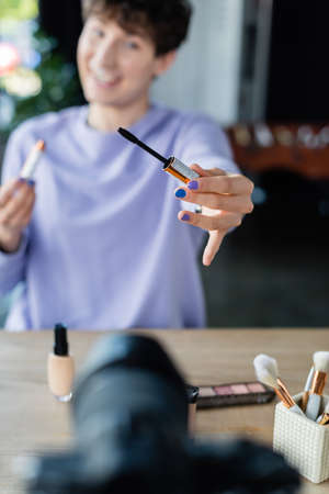 Mascara in hand of blurred transgender person near digital cameraの写真素材