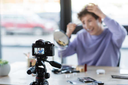 Digital camera near blurred transgender person with cosmetic brush and decorative cosmeticsの写真素材