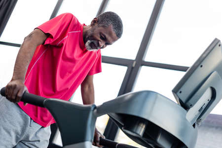 Low angle view of senior african american man training on treadmill in gym