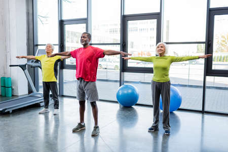 Interracial elderly people training together in sports centerの写真素材