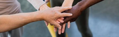 Cropped view of multiethnic people holding hands in sports center, banner