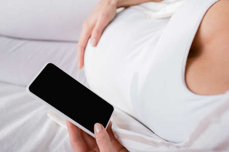 cropped view of pregnant woman holding smartphone with blank screenの写真素材