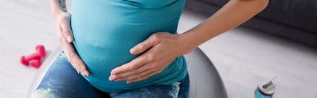 cropped view of pregnant sportswoman exercising on fitness ball, bannerの写真素材