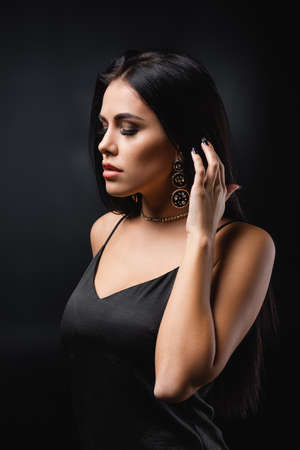 brunette young woman in slip dress posing on blackの写真素材