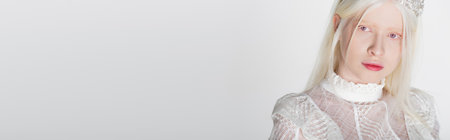 Pretty albino model in crown and blouse looking at camera isolated on white, banner