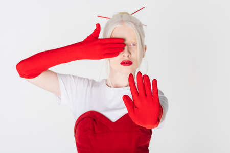 Blurred albino model in red gloves showing stop sign isolated on whiteの写真素材