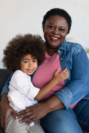 happy african american girl with granny looking at camera while embracing at homeの写真素材