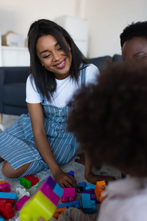 blurred african american kid playing building blocks game with happy mother and grannyの写真素材