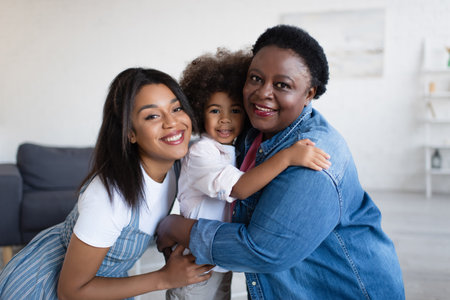 joyful african american women looking at camera while hugging toddler girl