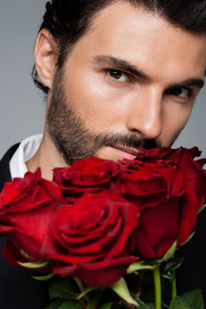 close up of bearded man holding bouquet of red roses isolated on greyの写真素材