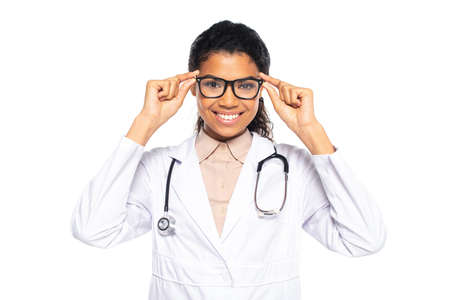 Smiling african american oculist holding eyeglasses isolated on whiteの写真素材