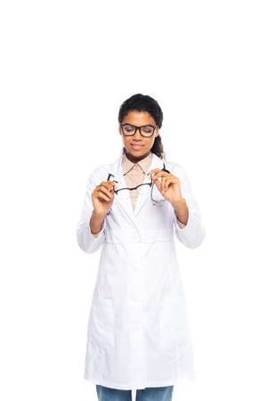Pretty african american doctor looking at optical eyeglasses isolated on whiteの写真素材