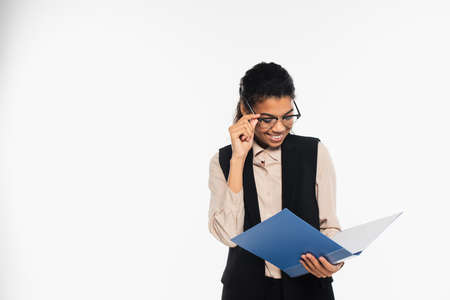 Happy african american businesswoman holding eyeglasses and paper folder isolated on whiteの写真素材