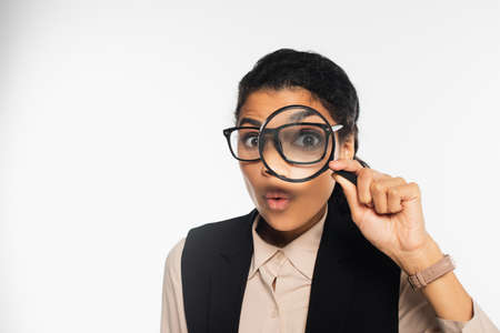Amazed african american businesswoman holding magnifying glass on whiteの写真素材
