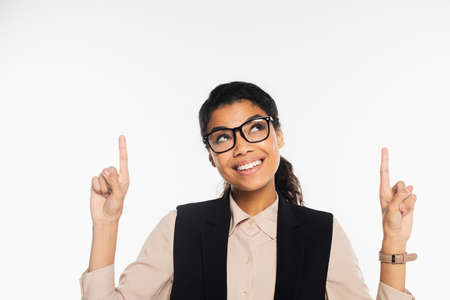 Cheerful african american businesswoman in eyeglasses pointing with fingers isolated on whiteの写真素材