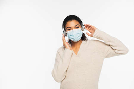 African american woman in medical mask and headphones isolated on whiteの写真素材
