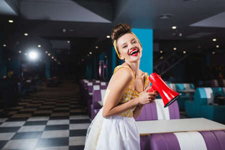 happy pin up woman with megaphone in cafe
