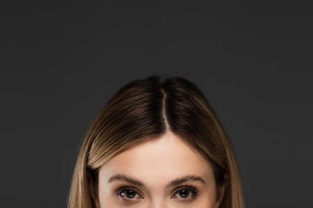 cropped view of young woman with natural makeup looking at camera isolated on greyの写真素材